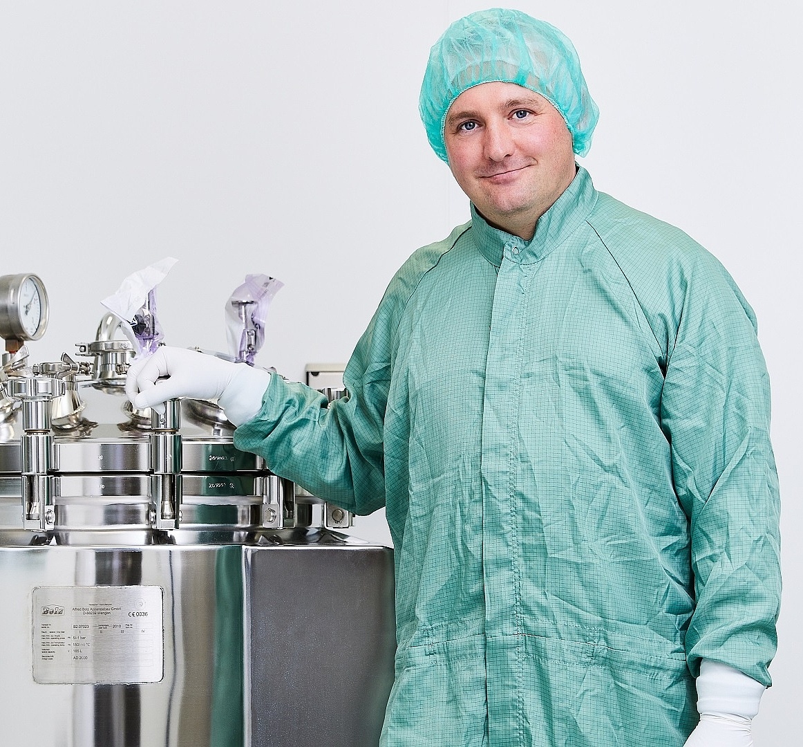 Portraitbild von einem Mitarbeiter in aseptische Kleidung an einer Maschine 