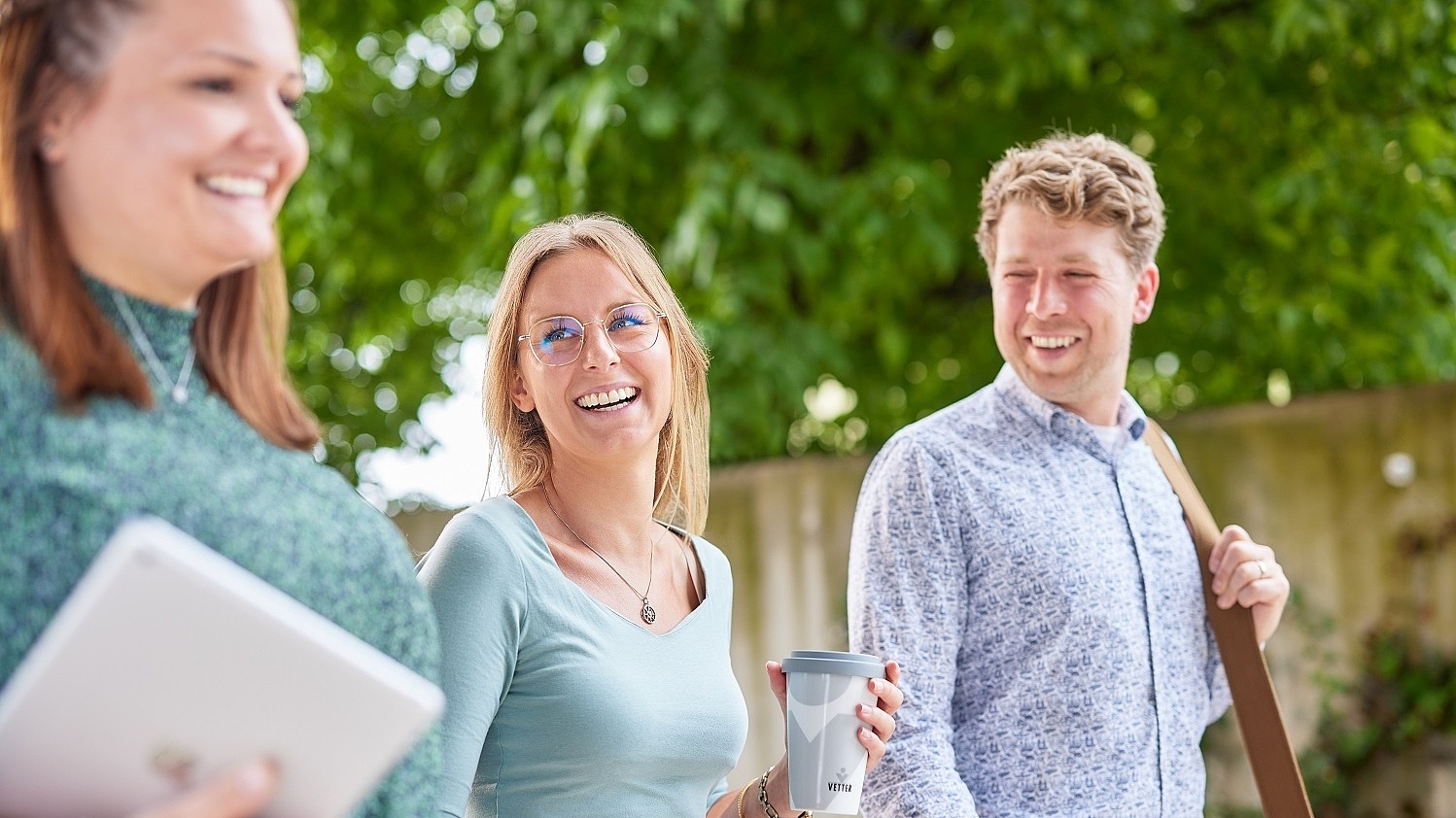 Vetter-Mitarbeitende gehen zusammen im Freien und lachen einander an