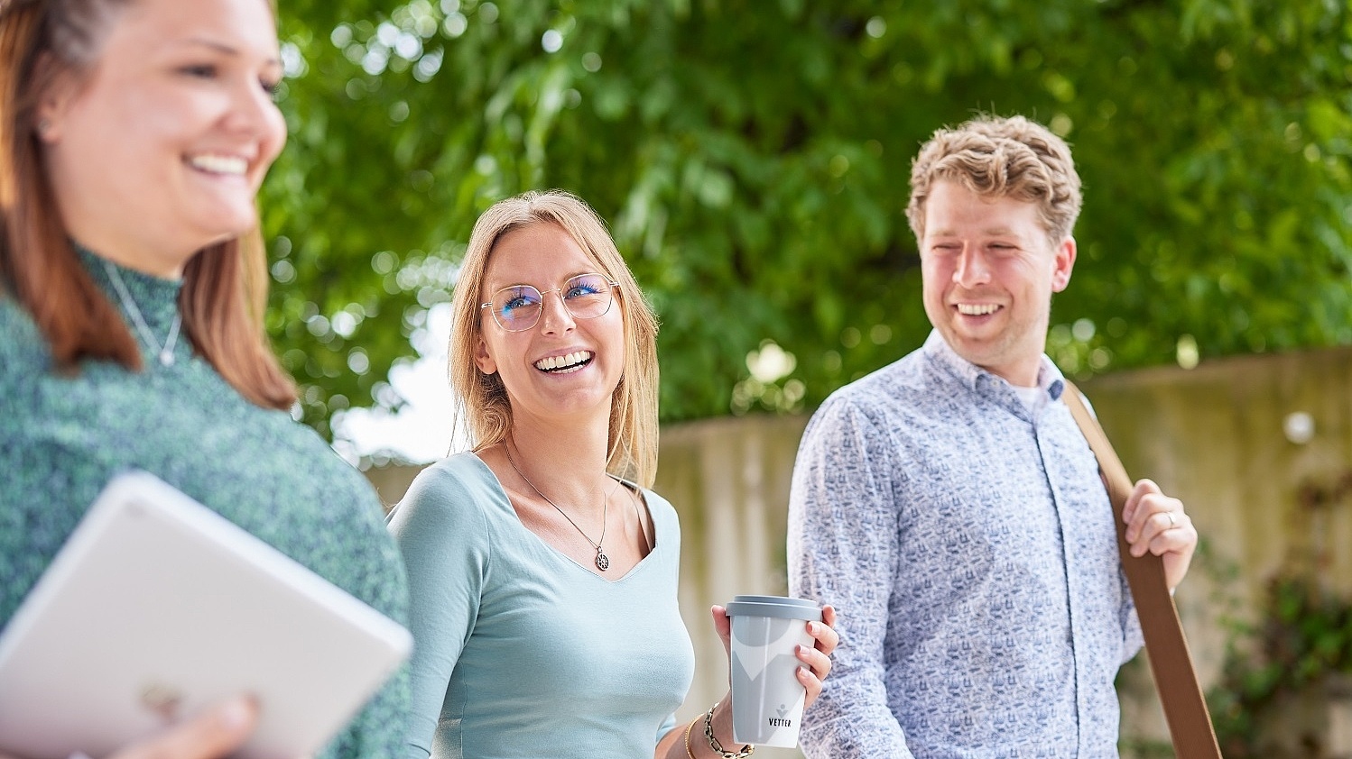 Vetter-Mitarbeitende gehen zusammen im Freien und lachen einander an