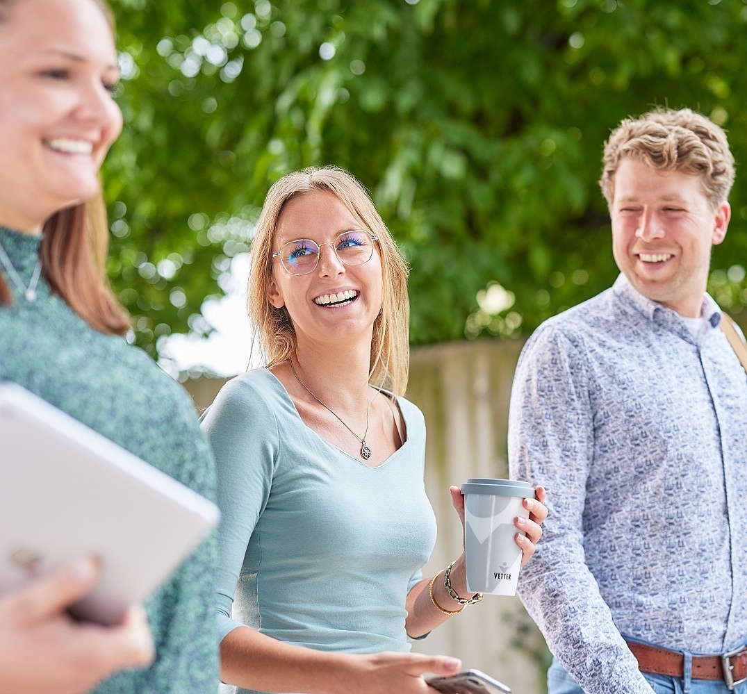 Vetter-Mitarbeitende gehen zusammen im Freien und lachen einander an