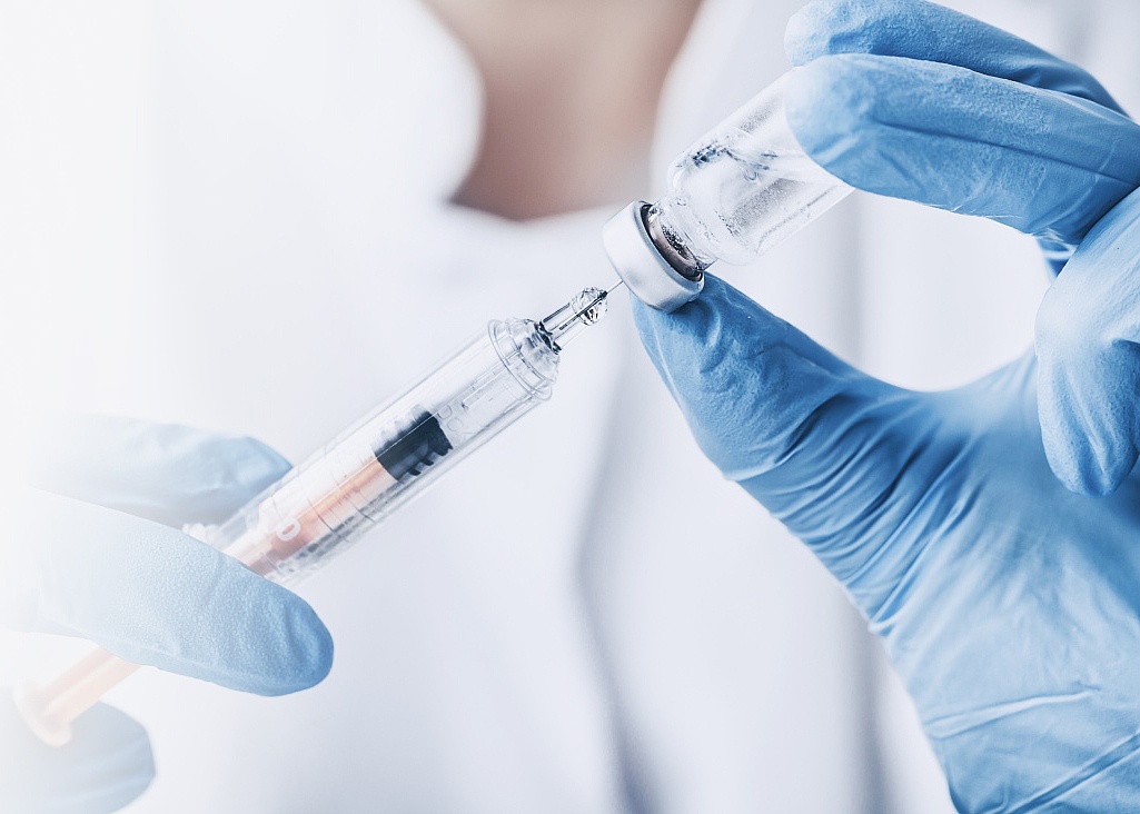 Hands holding a syringe and a vial. 