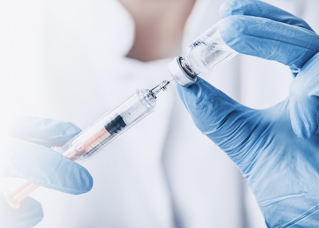 Hands holding a syringe and a vial. 