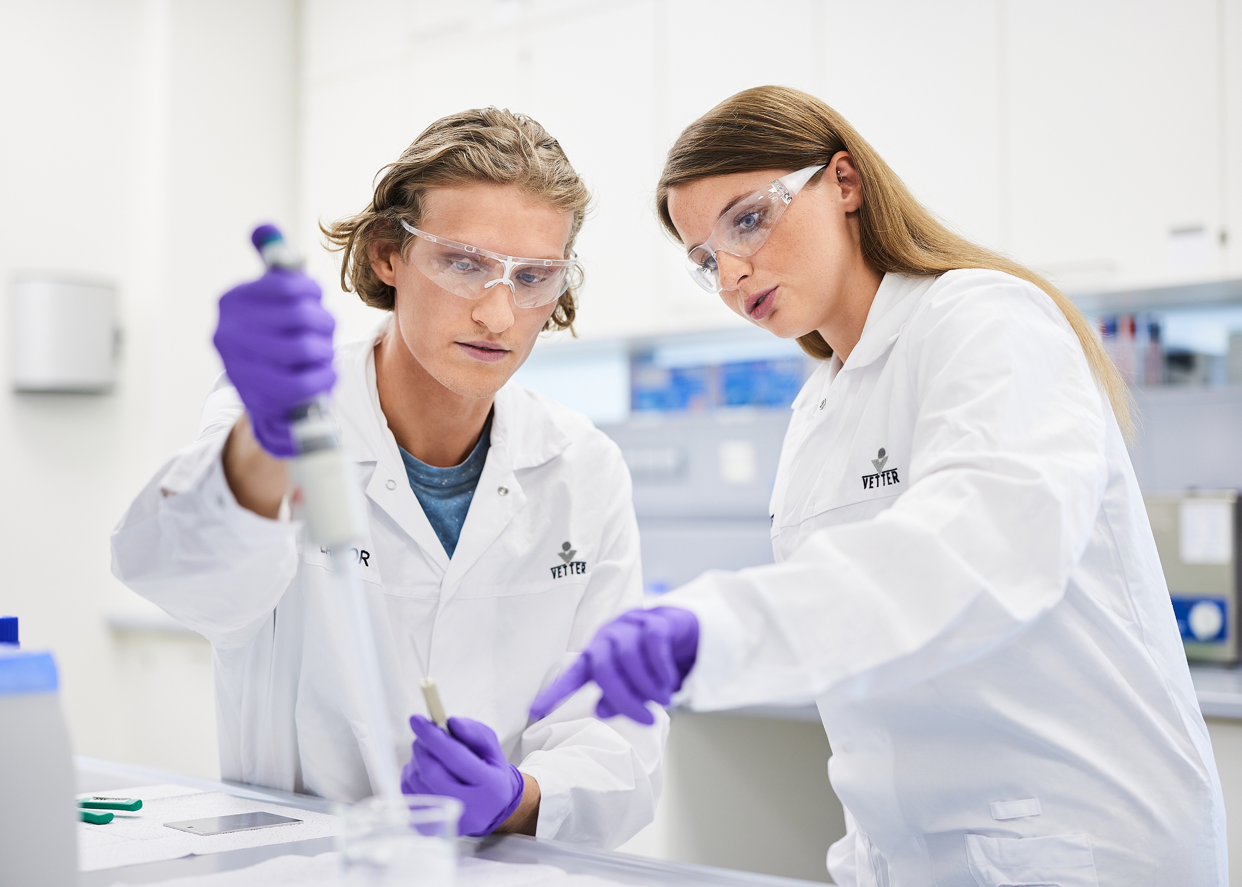 Zwei Auszubildende mit Laborkleidung in einem Labor