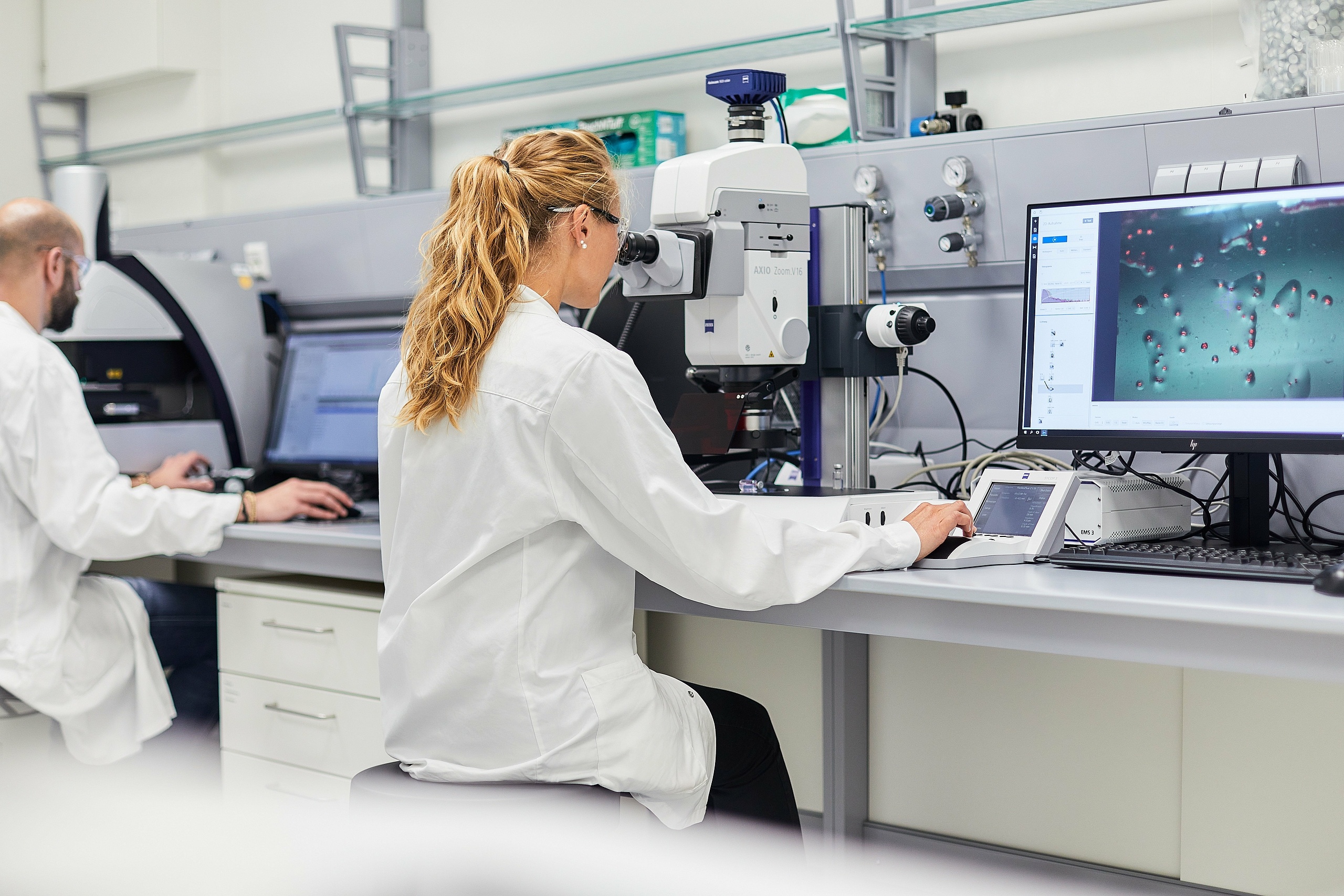 Woman looking through a microscope in an analytical service laboratory. 