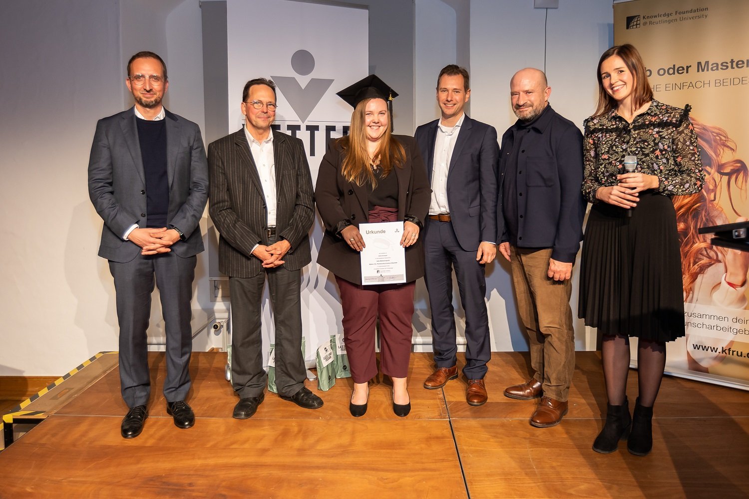 Gruppenbild mit einer Trainee die ihre Urkunde in der Hand hält 