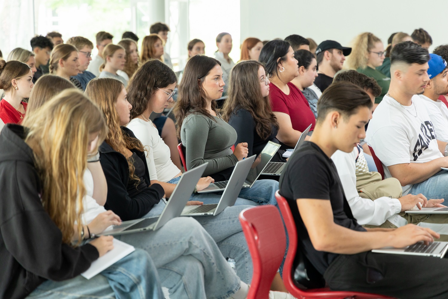 Azubi-Welcome-Tage 2024 bei Vetter: viele Auszubildende sitzen mit ihren Laptops auf dem Schoß in Stuhlreihen