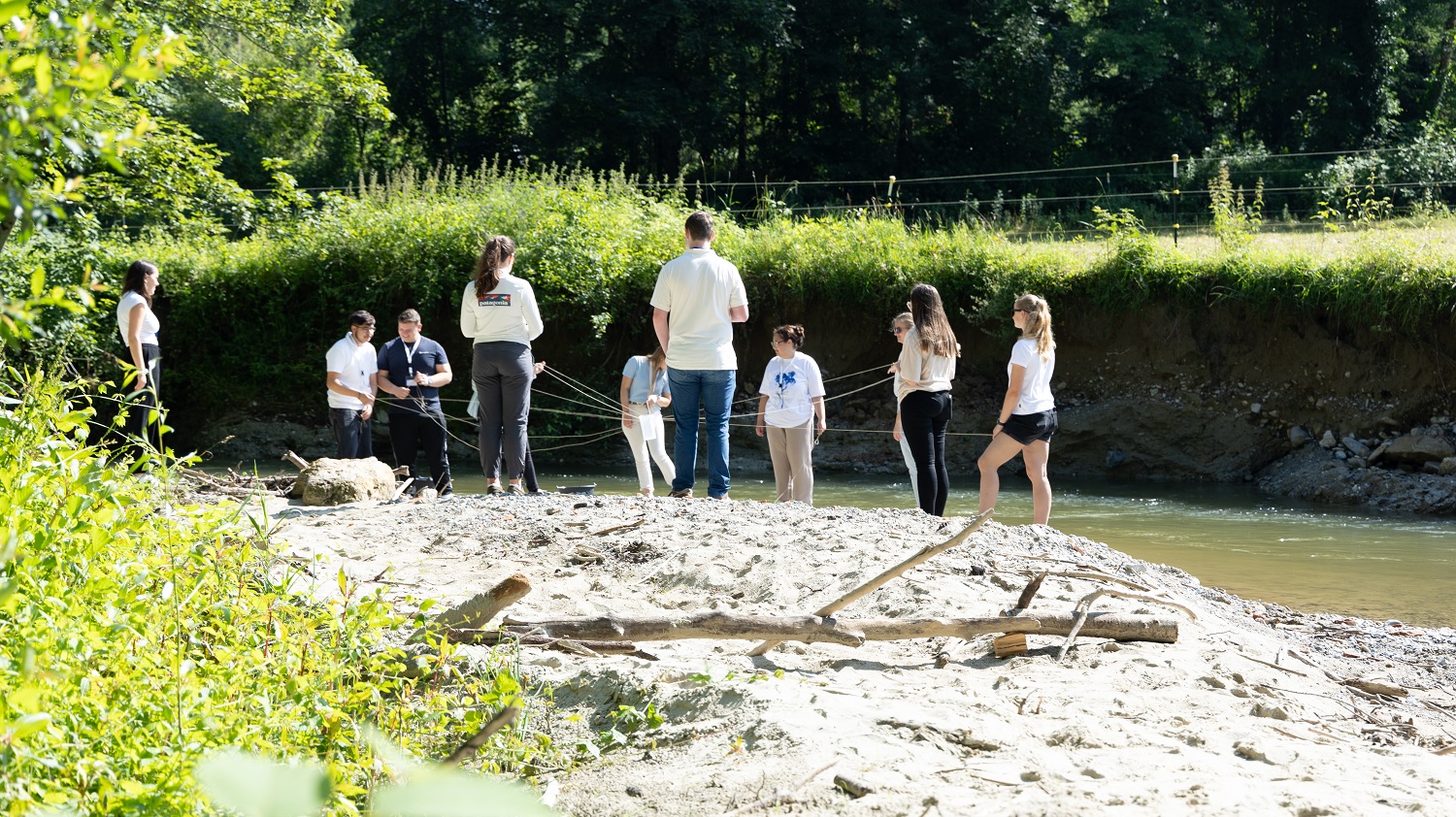 Azubi-Event 2024: Azubis bei einem Spiel am Fluss stehend