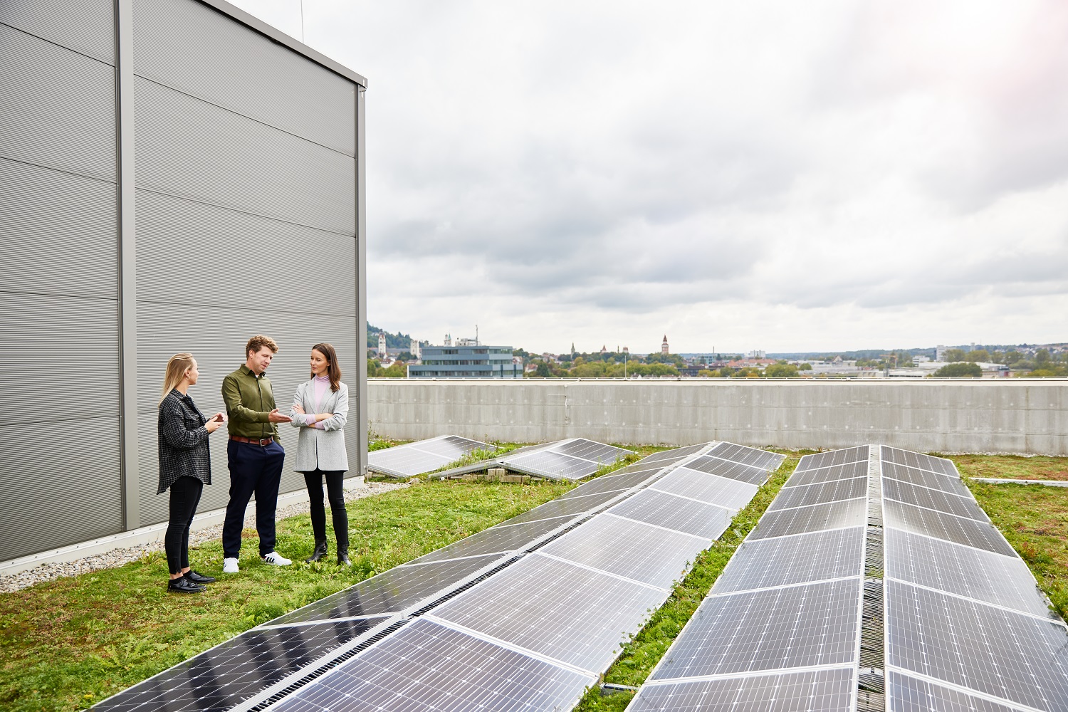 Mitarbeitende die auf einem Dach stehen uns sich über Photovoltaik unterhalten